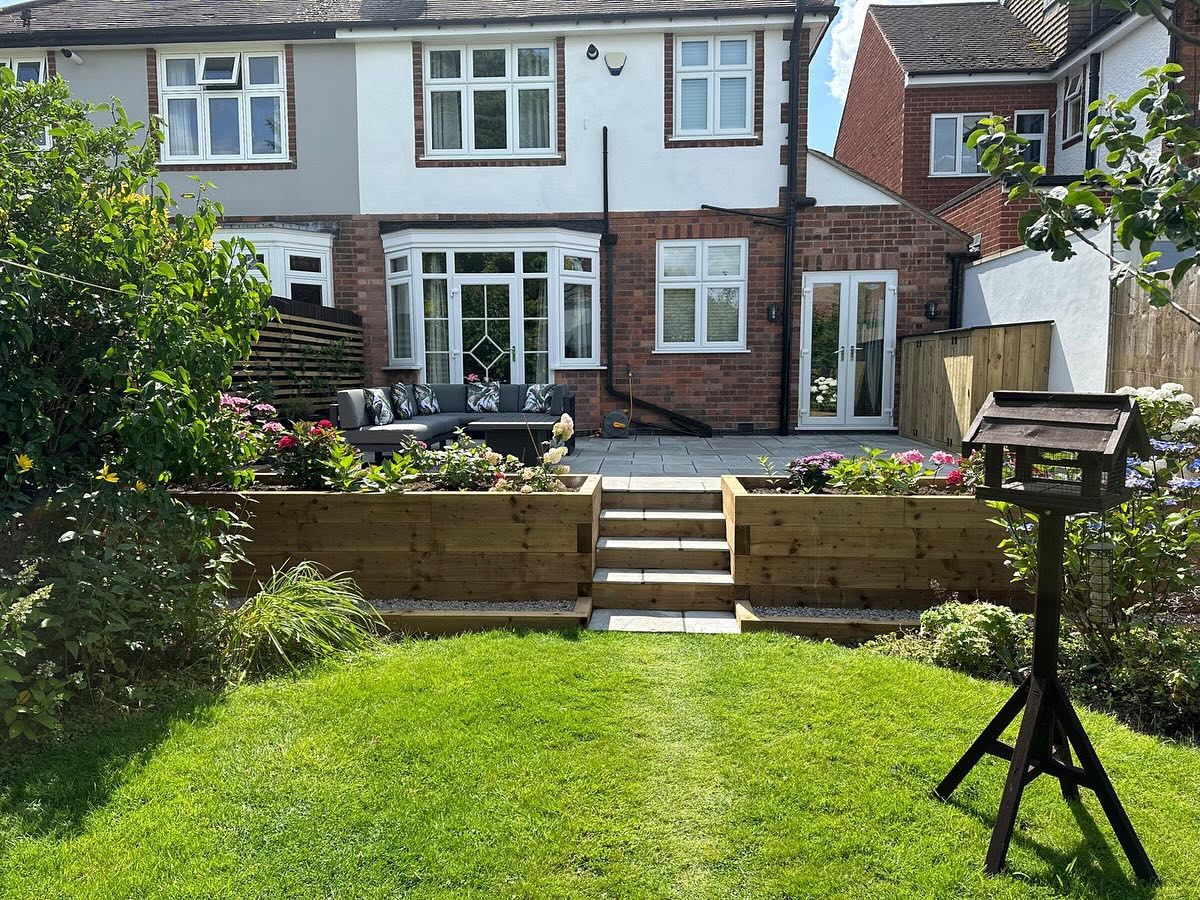 Back Garden Patio Birstall — grey porcelain patio with timber sleeper raised planters