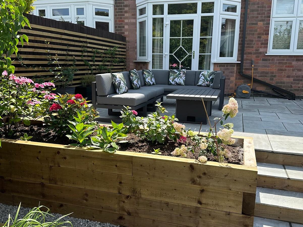Close-up of timber raised planter with hydrangeas and lounge furniture — Birstall