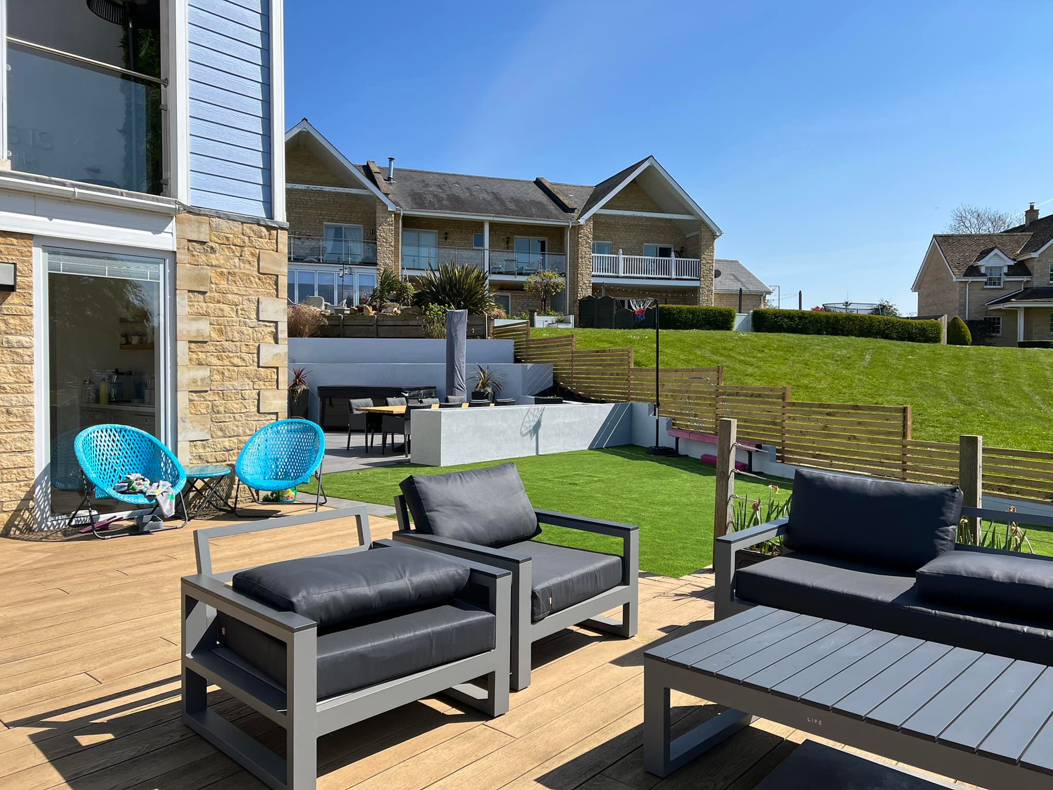Composite decking with lounge seating, artificial grass lawn and lake view, Peterborough