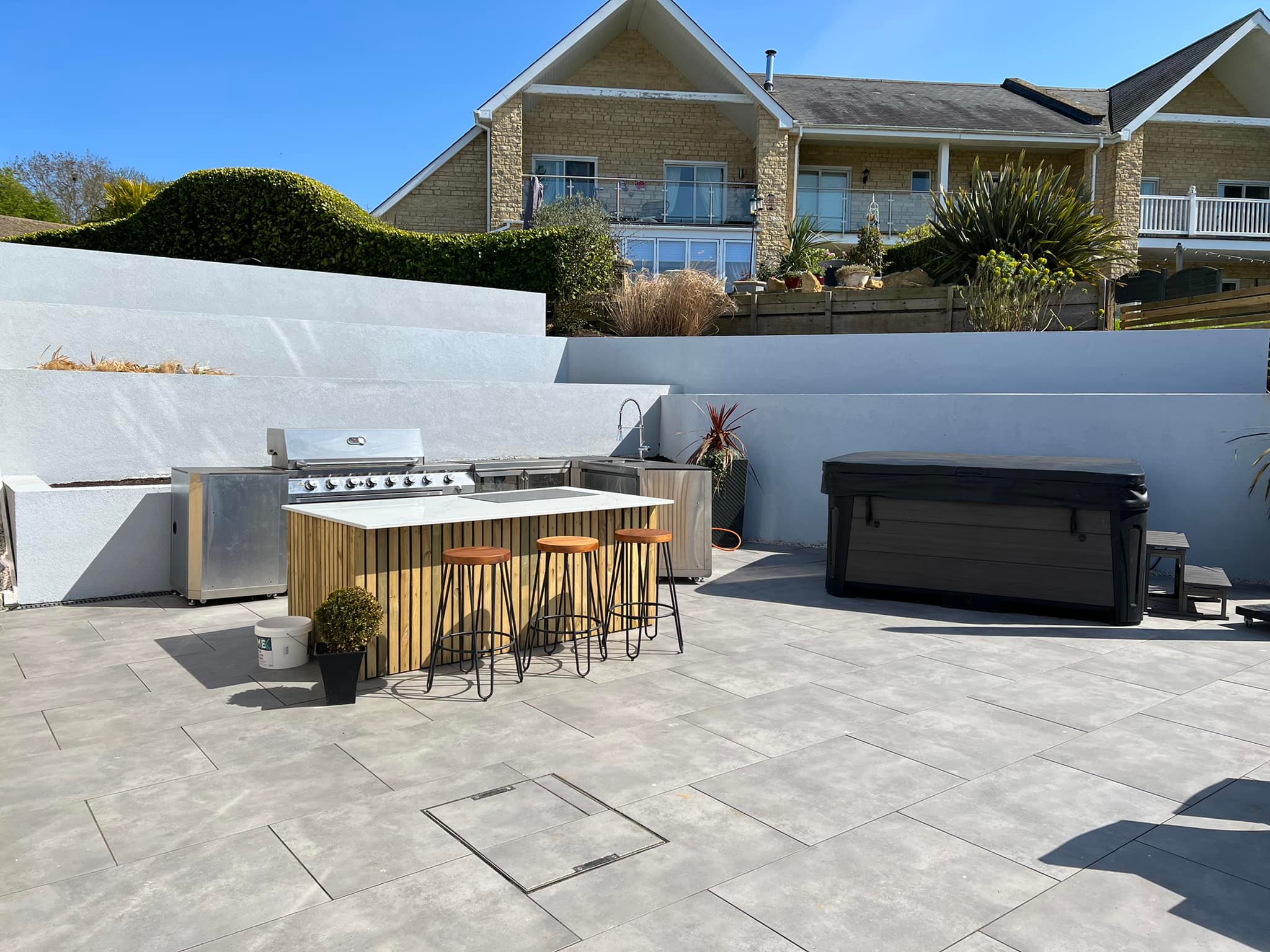 Outdoor kitchen island with BBQ and bar stools on large porcelain patio, Peterborough