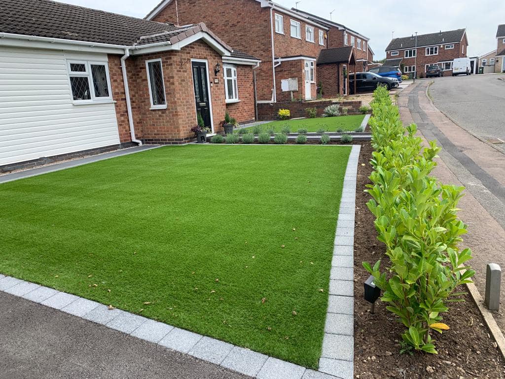 Street view of finished front garden with artificial grass and ornamental bay trees, Wigston